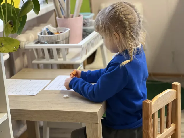 Mokinė savarankiškai dirba prie stalo Montessori klasėje