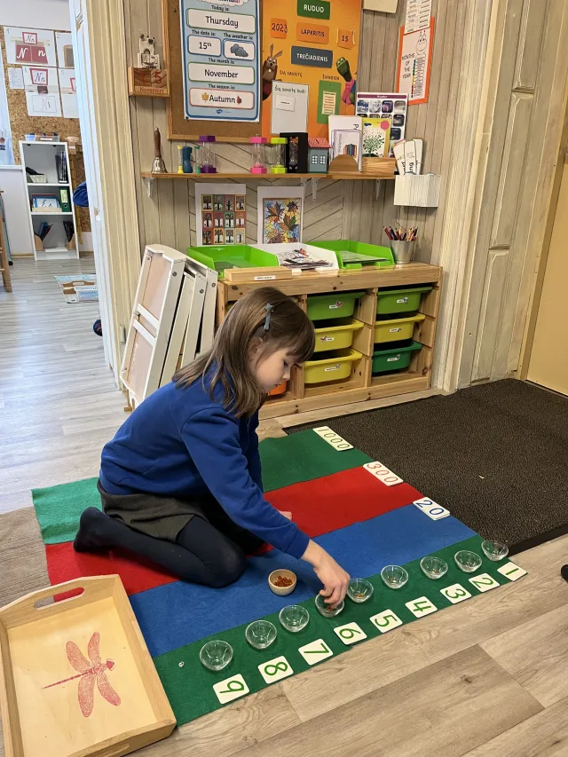 Mokinė dirba su Montessori matematikos priemonėmis